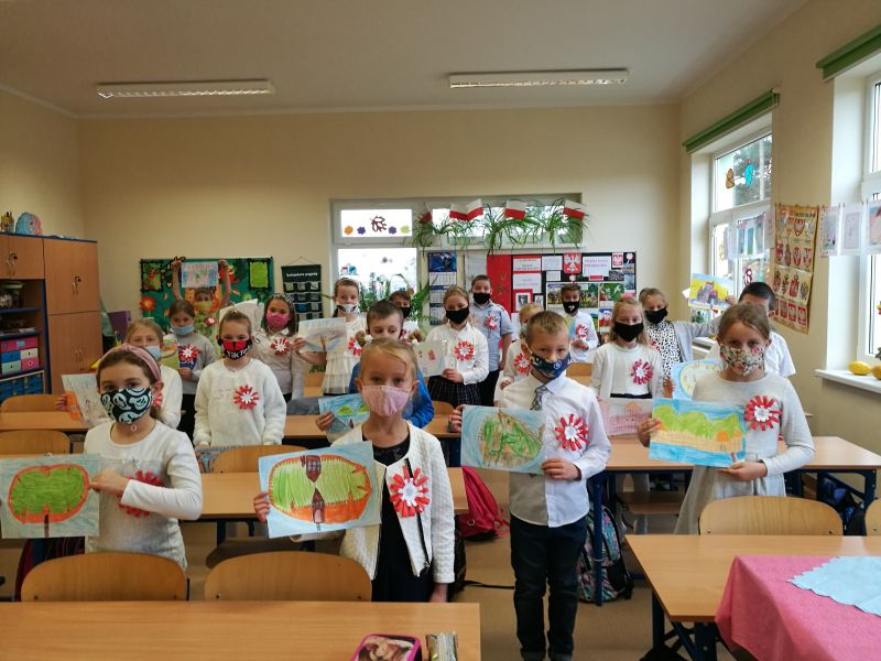 uczniowie w klasie z pracami w...